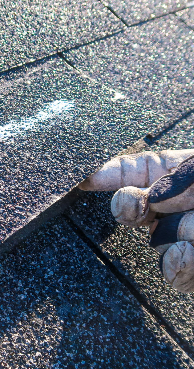 Roofer holding up loose roofing with finger