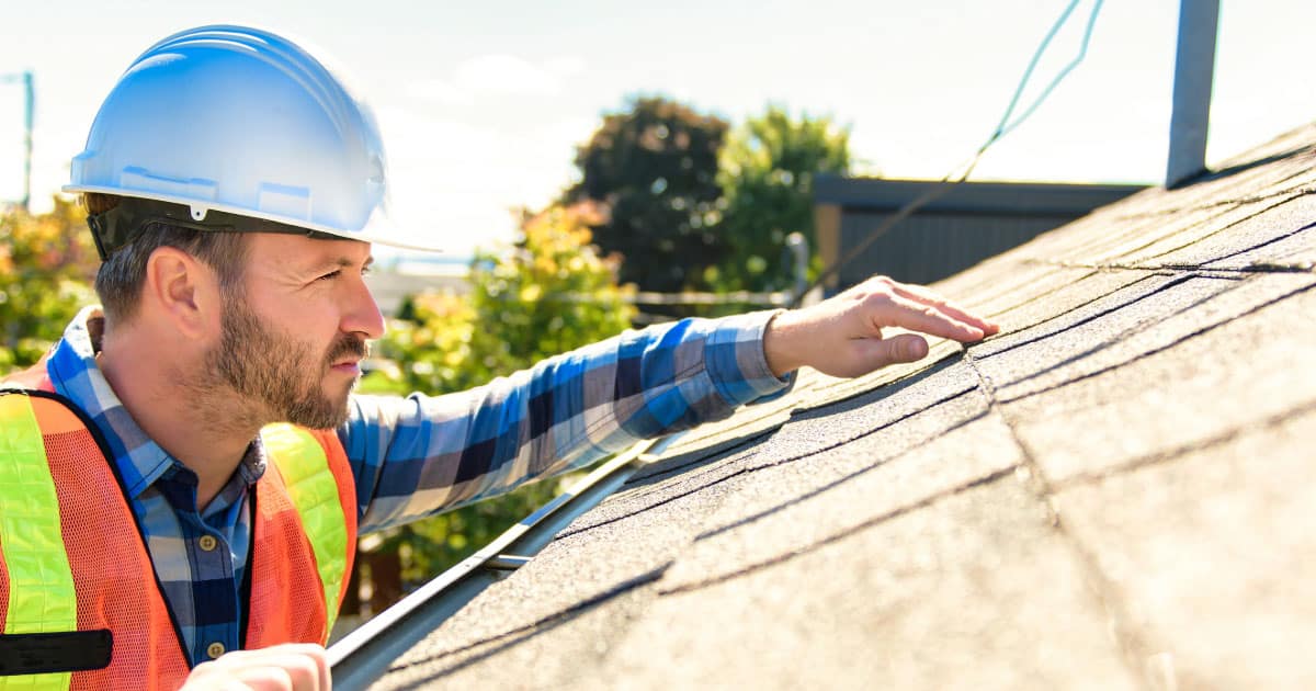 Roof inspector checking asphalt rolled roofing for damage