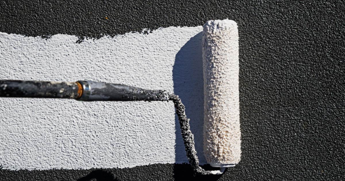 Paint roller applying white roof covering