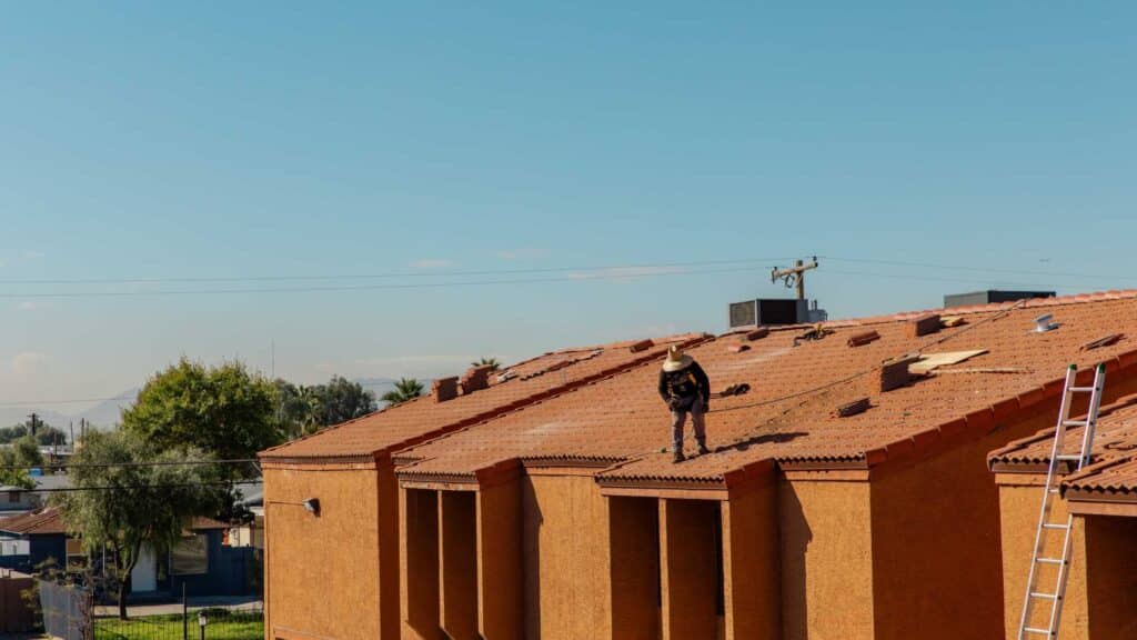 Roofer installing tile roofing on new Phoenix home construction showing roof installation work