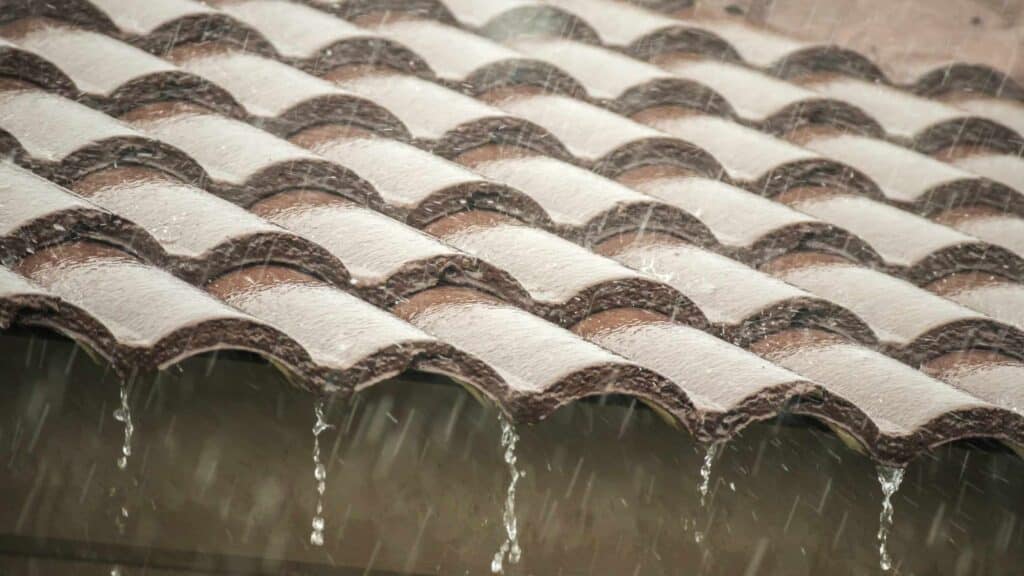 Water dripping from damaged tile roof during Arizona monsoon rain showing need for repair