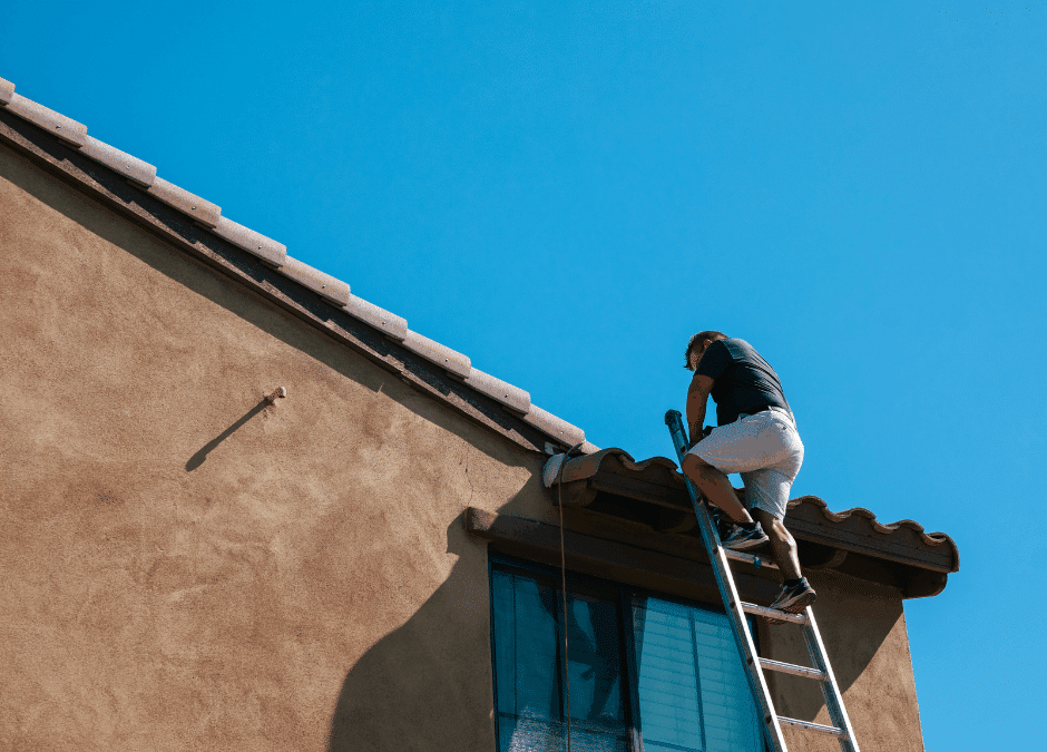Homeowner on ladder performing DIY roof maintenance on Phoenix house with tile roof