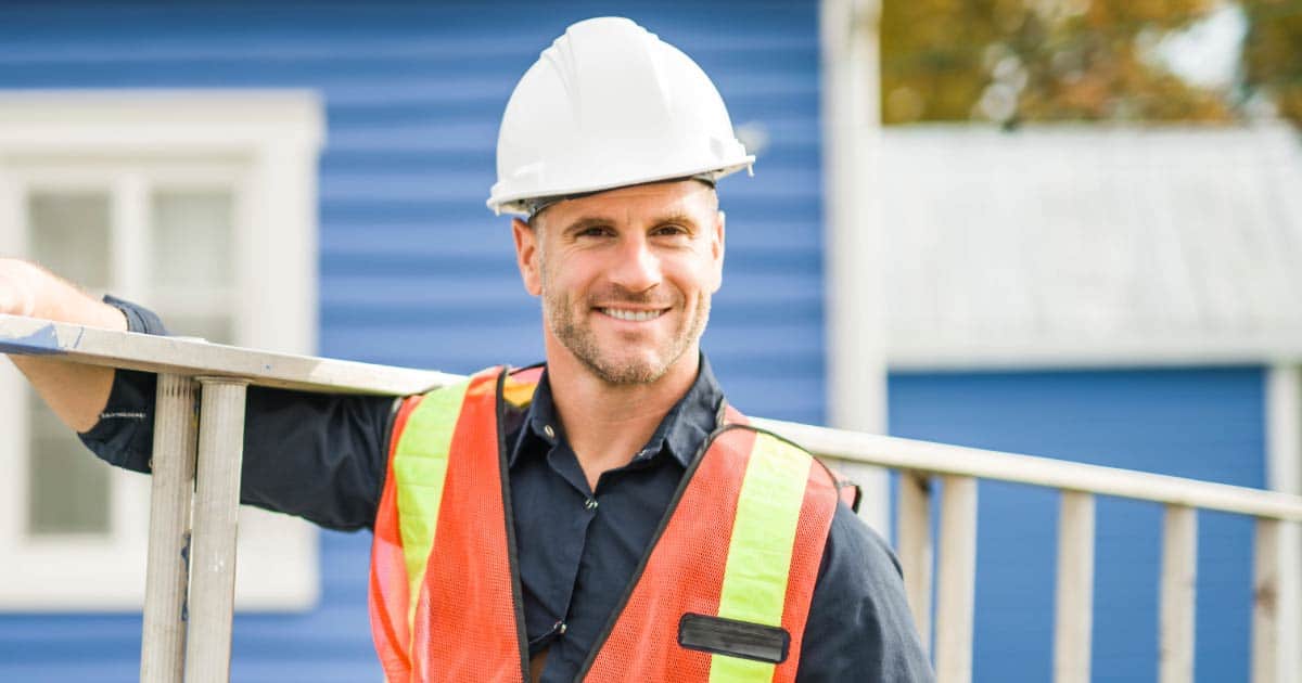Roofer preparing to climb onto a roof to inspect it holding ladder